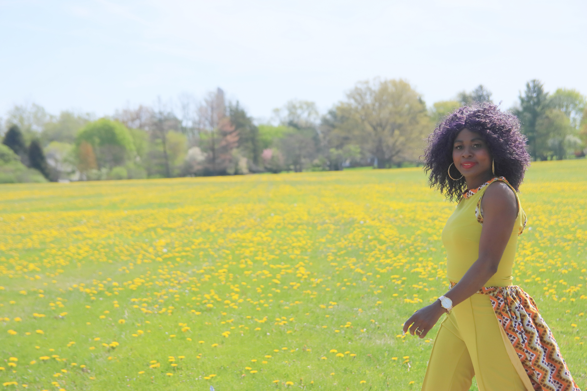 Woman wearing handmade bright yellow colored outfit in a field of dandelions 