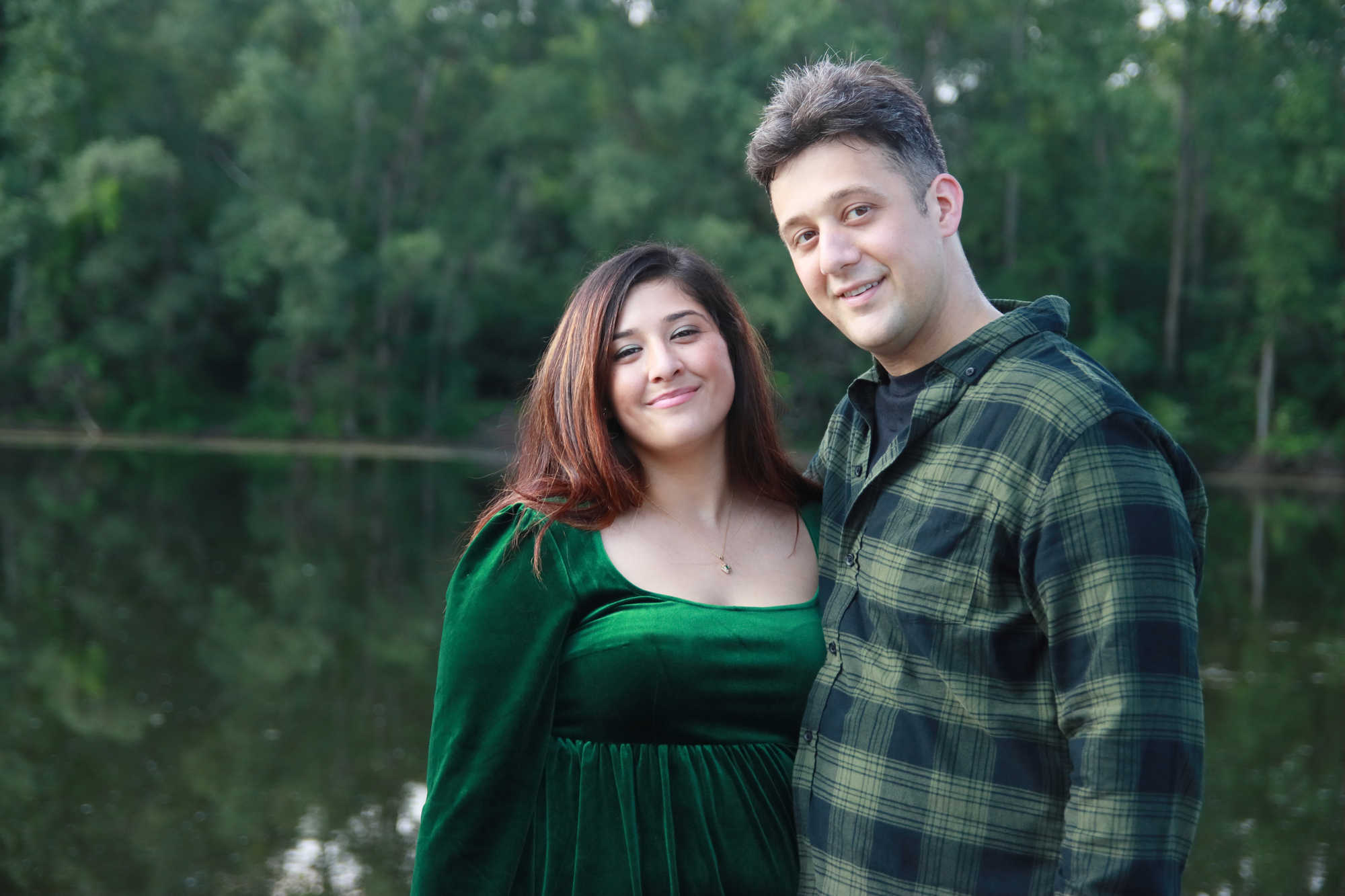 a woman with a bright green dress is hugging her fiancé who is wearing a green flannel shirt