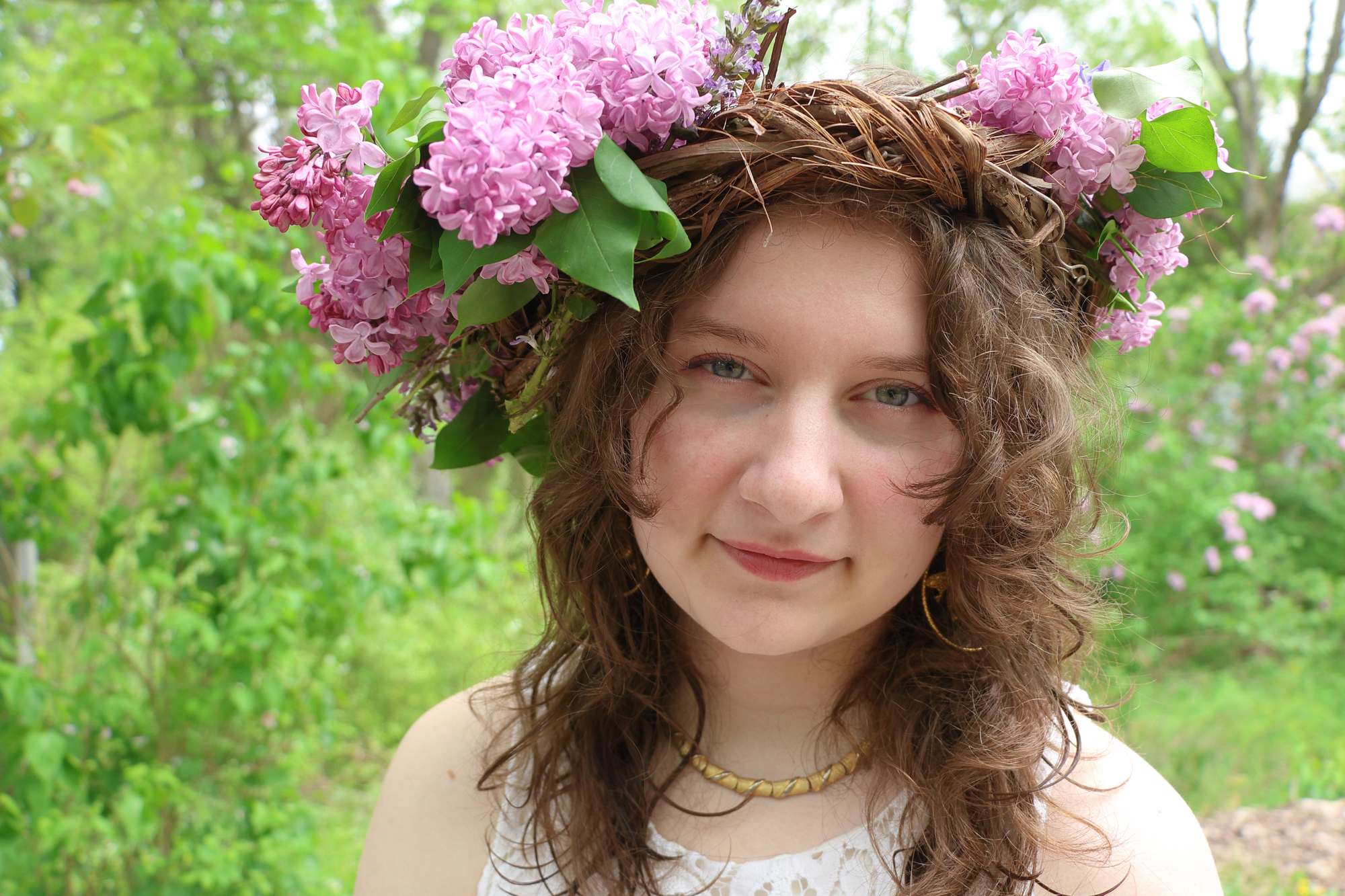 Young woman with a lilac flower and a bouquet of lilacs 